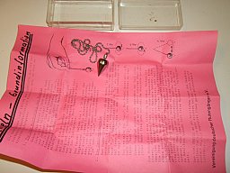 Metallpendel an Kette mit einer Information und Einweisung der Vereinigung deutscher Rutengänger e.V